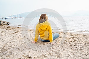 Lonely beautiful sad girl teenager sits thoughtfully on sand sea beach. Dreams,anxiety,worries about future,school