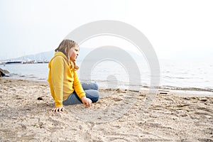 Lonely beautiful sad girl teenager sits thoughtfully on sand sea beach. Dreams,anxiety,worries about future,school