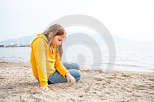 Lonely beautiful sad girl teenager sits thoughtfully on sand sea beach. Dreams,anxiety,worries about future,school