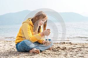 Lonely beautiful sad girl teenager sits thoughtfully on sand sea beach. Dreams,anxiety,worries about future,school