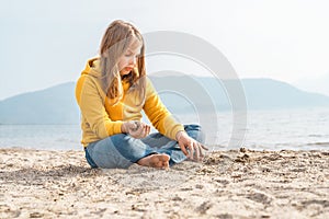 Lonely beautiful sad girl teenager sits thoughtfully on sand sea beach. Dreams,anxiety,worries about future,school