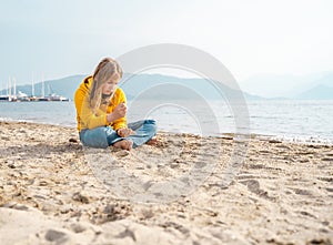 Lonely beautiful sad girl teenager sits thoughtfully on sand sea beach. Dreams,anxiety,worries about future,school