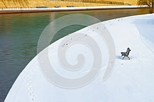 Lonely bench in the snow over the river