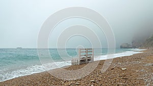A lonely bench stands on the shore of the sea beach.