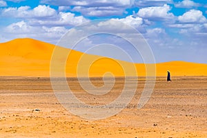 Lonely berber man walking in desert, Merzouga, Sahara Desert, Morocco