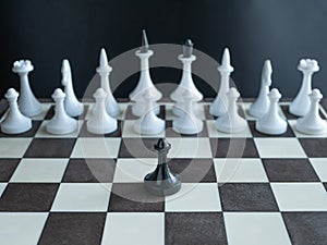 Lonely black pawn standing alone against whole army of white figures on chess board. concept depict one man army famous Martin