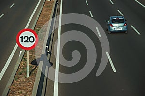 Lonely blue car on highway and SPEED LIMIT signpost in Madrid photo