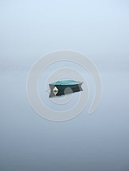 A lonely boat on a misty lake. Lake Neyetalsperre in the German city of WipperfÃ¼rth in the Bergisches Land region