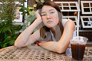 Lonely bored Asian woman waiting for her friend alone in the coffee shop.