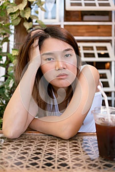 Lonely bored Asian woman waiting for her friend alone in the coffee shop.