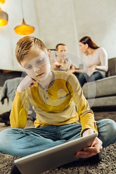 Lonely boy playing on tablet while parents fighting