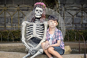 Lonely Boy Sits Next to a Skeleton in a Park