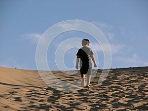 Lonely boy trekking in the dunes