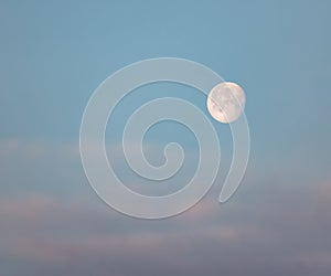 Lonely bright moon in the morning cloudy blue sky