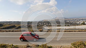 Lonely car driving along quiet road in mountainous terrain of Santorini island