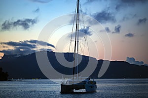 Lonely catamaran against the background a golden sunset near Bora-Bora island