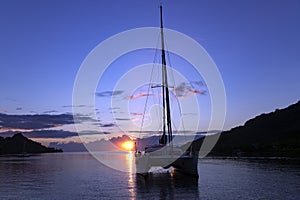 Lonely catamaran in a quiet lagoon at sunset photo