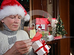 Lonely Caucasian senior woman in Santa hat on video call on laptop, with christmas tree and gifts