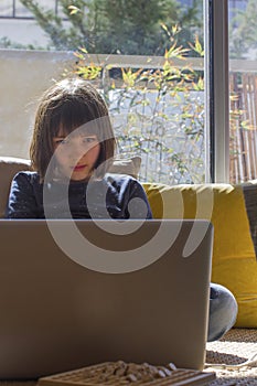 Lonely child hypnotized by computer for homeschool learning, screen overdose