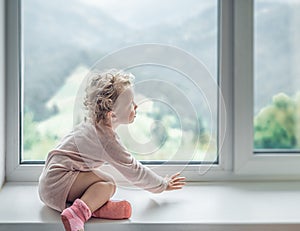 Lonely child looks out the window.