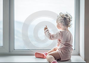 Lonely child looks out the window.