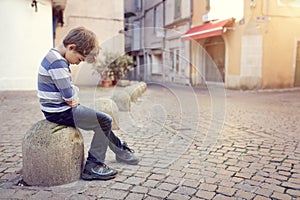 Lonely child sitting on a street corner