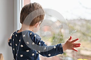 Lonely child by the window. Sad lonely child sitting alone on the window at home