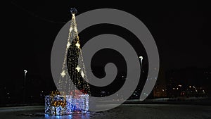 Lonely Christmas tree in the empty city street at night. Concept. City park with decorated beautiful spruce tree with