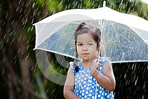 Lonely cute asian little girl with umbrella in rain