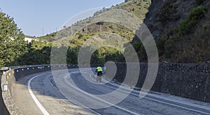 A lonely cyclist biking in an empty spanish road in the summer
