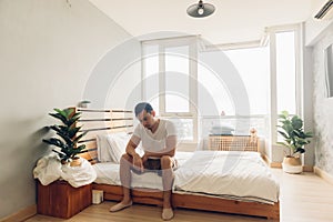 Lonely and depressed man in his bedroom in the apartment.