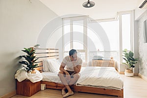 Lonely and depressed man in his bedroom in the apartment.