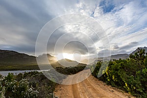 Lonely dirt road leading into a mountain range at sunset