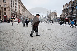 Lonely elderly man walk down the snow street