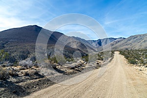 Lonely empty dirt road in the Mojave Desert under a blue sky