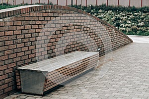 Lonely empty wooden bench on a brick wall background