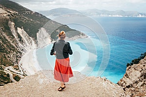 Lonely female enjoying Myrtos Beach viewpoint - unique turquoise water landmark seashore with bright white pebbles often