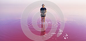 A lonely figure of a man against the background of a huge pink lake.