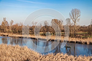 Lonely fisherman on the green wooden on small river boat fishing with fisherman\'s stick