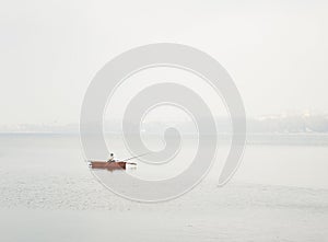 A lonely fisherman rows in a boat in the lake