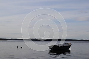 Lonely fishing boat docked in calm lake. wooden fishing boat in a still lake water. image of wooden fishing boat moored on the sho