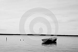 Lonely fishing boat docked in calm lake. wooden fishing boat in a still lake water. image of wooden fishing boat moored on the sho