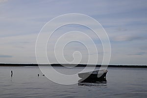 Lonely fishing boat docked in calm lake. wooden fishing boat in a still lake water. image of wooden fishing boat moored on the sho