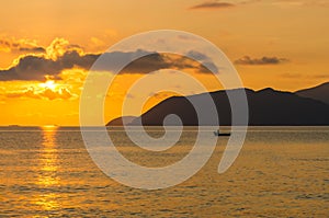 Lonely fishing boat in sea at dawn with reflection of sunlight in water