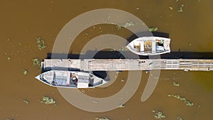 Lonely fishing boats and wooden pier in the lake. Aerial photo, top view