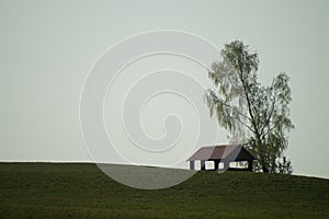 Lonely gazebo on the hill. summerhouse under tree standing alone in the field. solitude concept