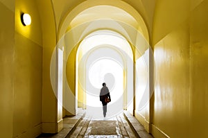 Lonely girl going forward through the yellow tunnel