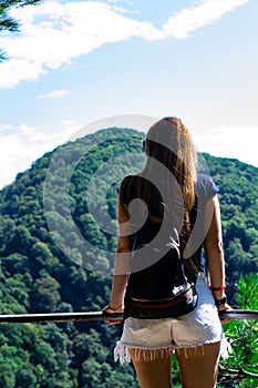 A lonely girl looks at the mountains on the other side. Low lying clouds and mountains