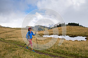 Lonely girl practicing Nordic walking with hiking sticks in the