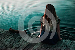 Lonely girl sitting in fornt of bog lake